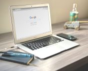 A laptop next to a notebook with Google on the screen.